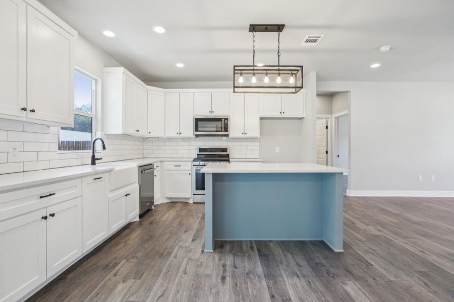 Kitchen featuring white cabinets, pendant lighting, backsplash, stainless steel appliances, and recessed lighting