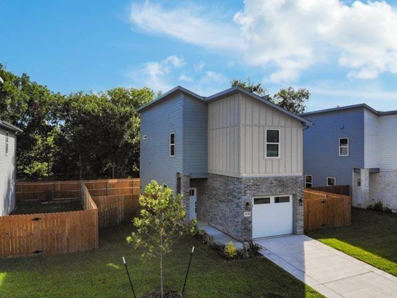 View of side of home with board and batten siding, a garage, brick siding, and driveway View of side of home with board and batten siding, a garage, brick siding, and driveway