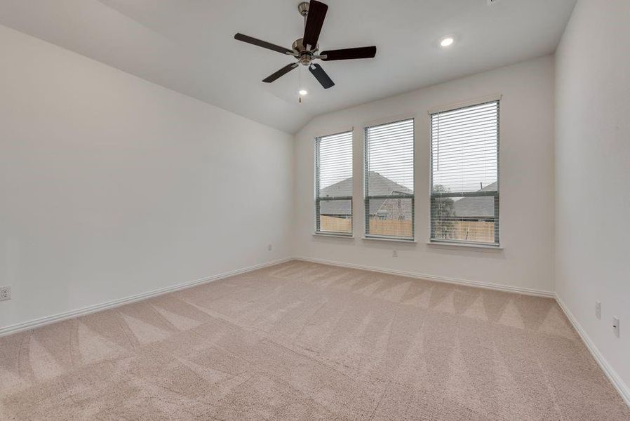 Spare room featuring ceiling fan, carpet floors, and vaulted ceiling