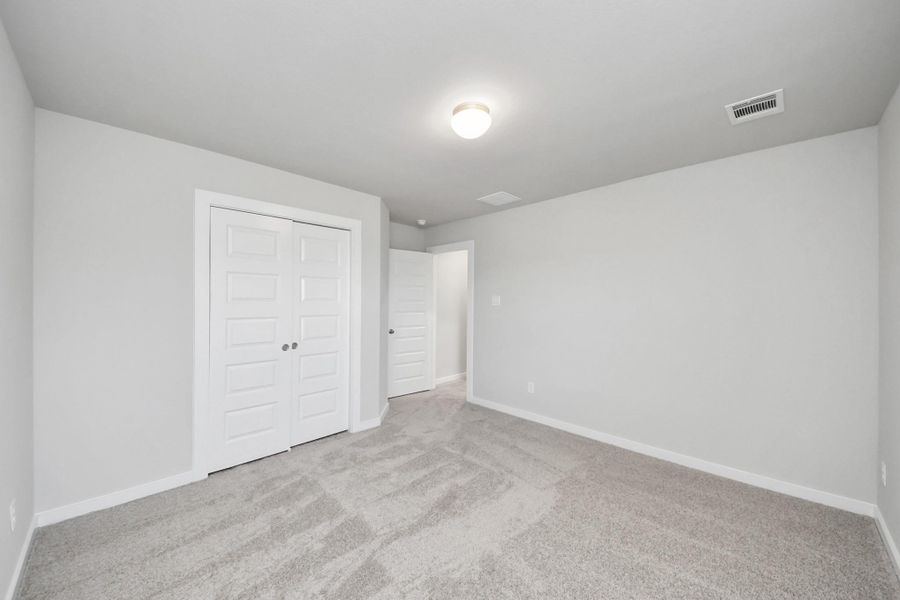 Generously sized secondary bedrooms featuring spacious closets, soft and inviting carpeting underfoot, large windows allowing plenty of natural light. Sample photo of completed home with similar plan. Actual colors and selections may vary. Call for more info.