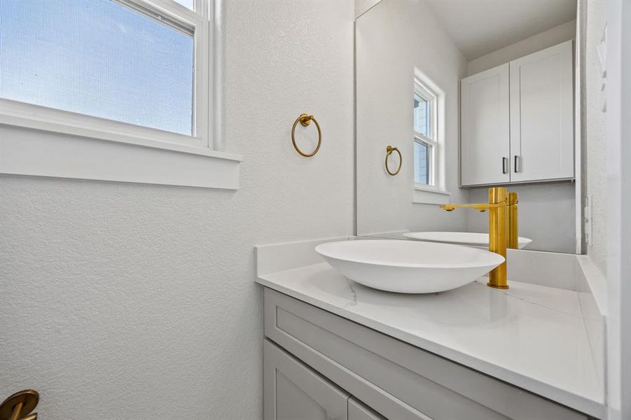 Bathroom featuring a textured wall and vanity