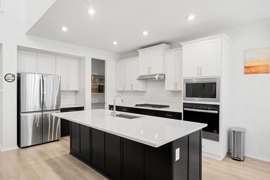 Kitchen featuring dark cabinetry, white cabinetry, appliances with stainless steel finishes, decorative backsplash, and recessed lighting Kitchen featuring dark cabinetry, white cabinetry, appliances with stainless steel finishes, decorative backsplash, and recessed lighting