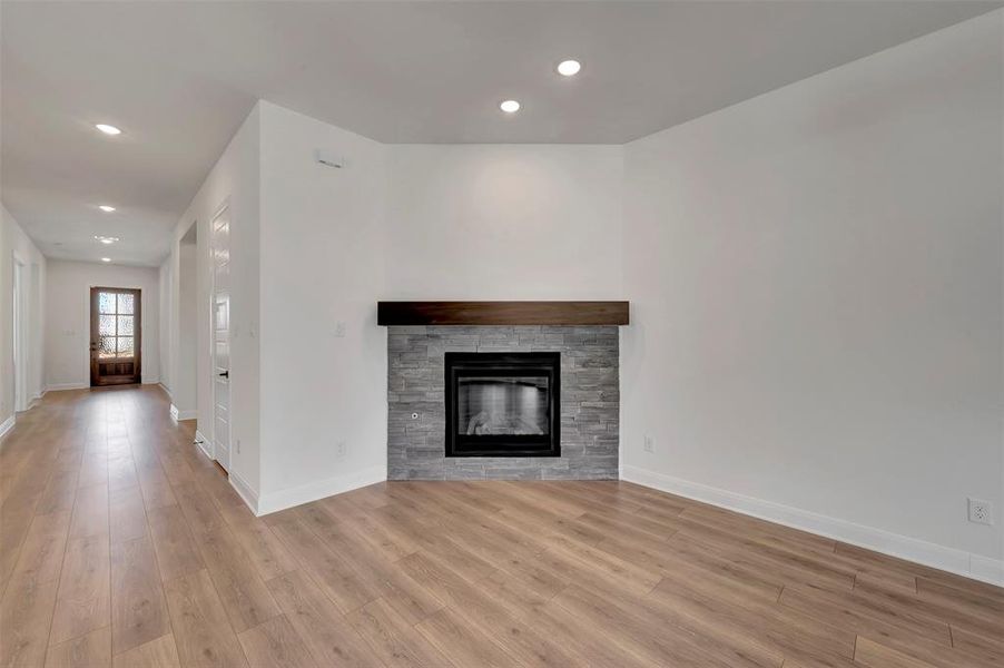 Unfurnished living room with light wood-style floors, a stone fireplace, and recessed lighting