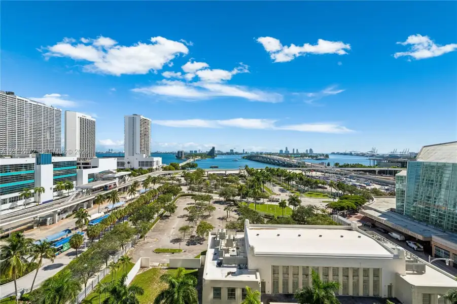 Urban skyline backdrop featuring a coastal waterway, elevated bridge infrastructure, and mature palm trees