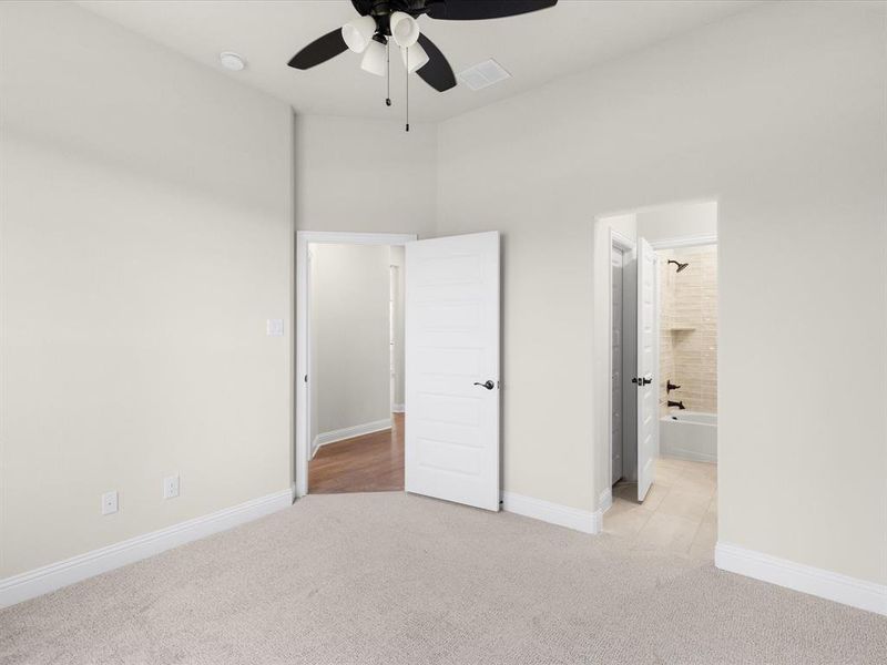 Unfurnished bedroom with light carpet, ceiling fan, and connected bathroom