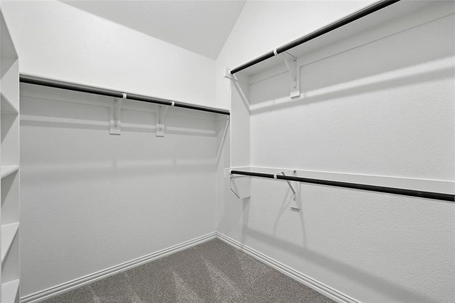 Walk in closet with dark colored carpet and vaulted ceiling