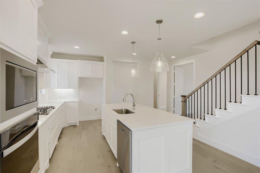 Modern kitchen featuring white cabinetry, light-toned countertops, and stainless steel appliances