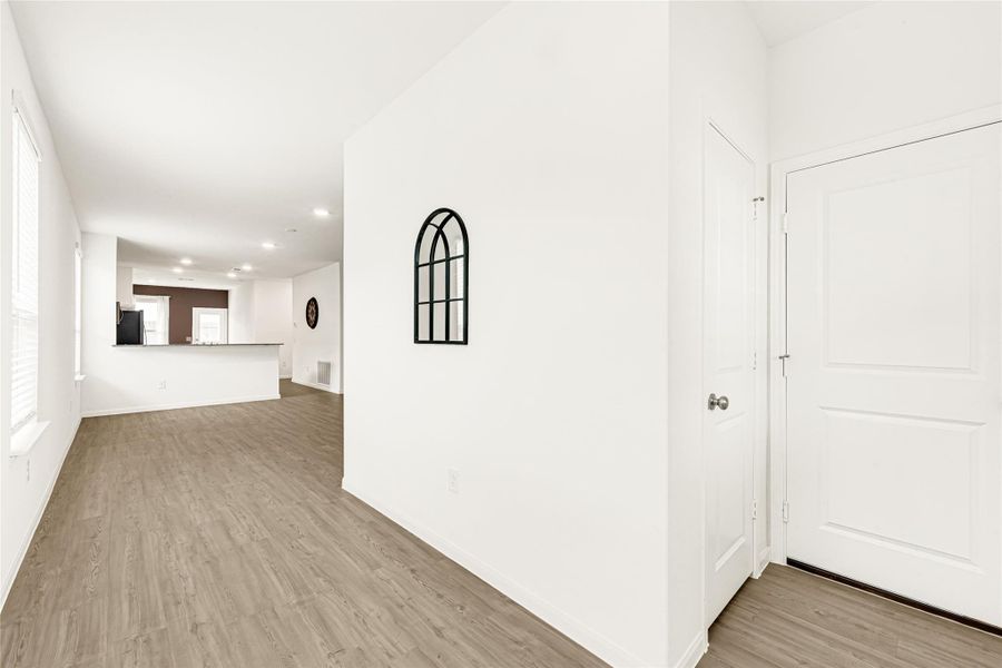 Bright, inviting hallway featuring neutral tones and a clear view towards the main rooms.