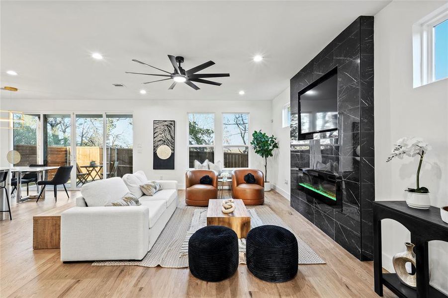 Living area featuring ceiling fan, recessed lighting, visible vents, a high end fireplace, and light wood finished floors