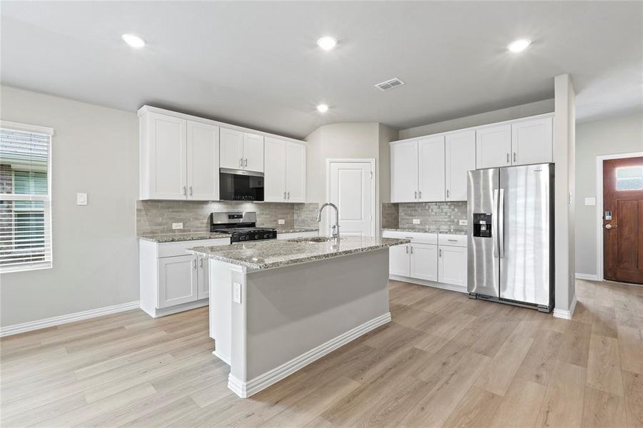 Kitchen featuring stainless steel appliances, backsplash, light wood-style flooring, recessed lighting, and white cabinetry Kitchen featuring stainless steel appliances, backsplash, light wood-style flooring, recessed lighting, and white cabinetry