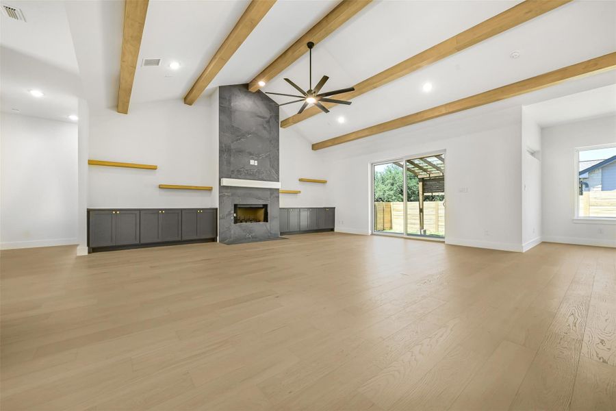 Unfurnished living room featuring ceiling fan, light wood-style flooring, a premium fireplace, beamed ceiling, and recessed lighting