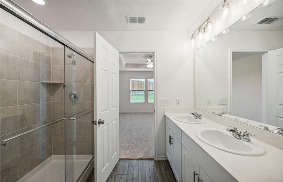 Owner's suite with dual vanity and oversized shower *real home pictured