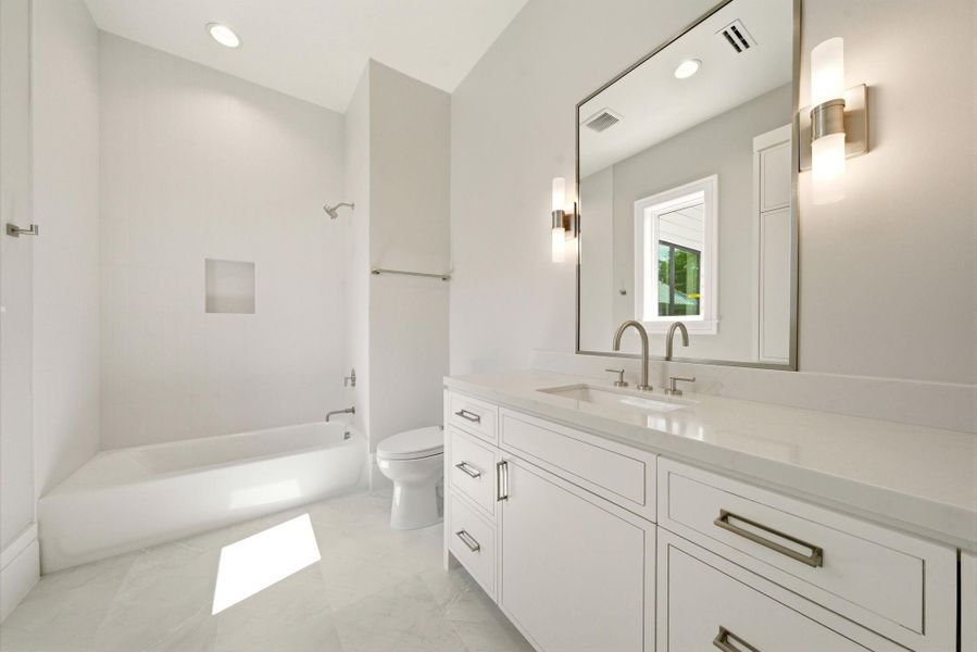 Bright secondary bathroom with quartz countertops, soaking tub/shower combination, and timeless neutral white finishes. Bright secondary bathroom with quartz countertops, soaking tub/shower combination, and timeless neutral white finishes.