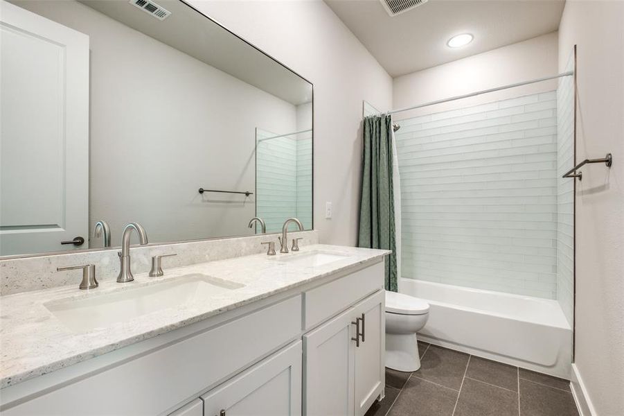 Full bathroom with vanity, shower / tub combo, toilet, and tile patterned floors