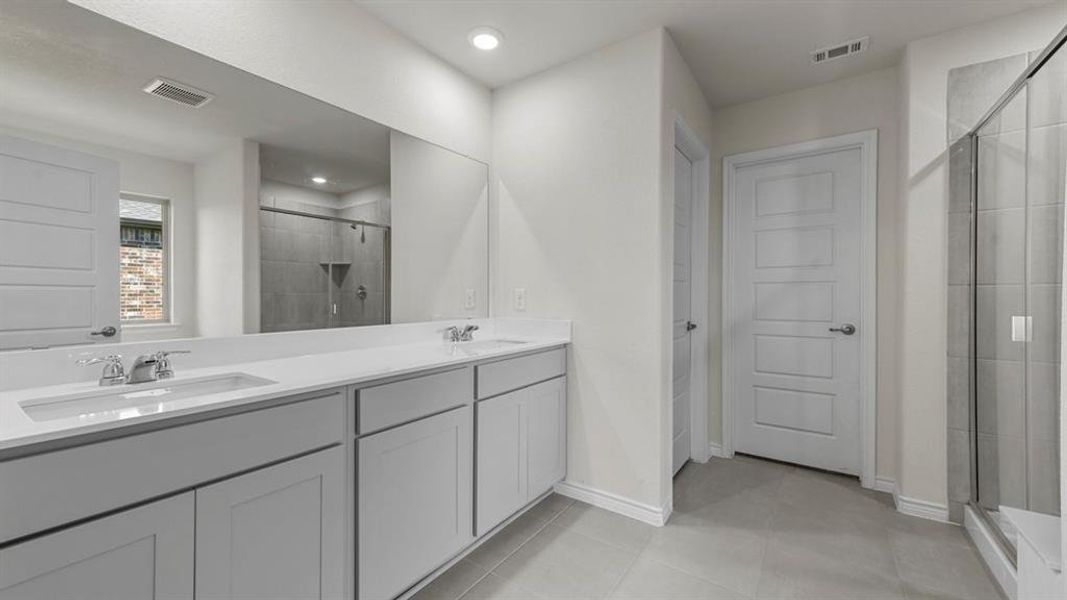 Bathroom featuring a double vanity with white countertops, chrome fixtures, and a large mirror