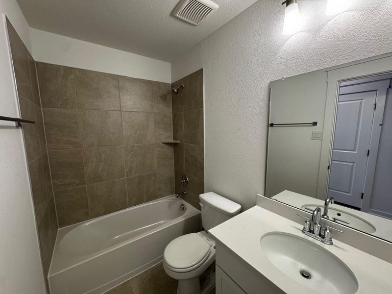 Full bathroom with a textured wall, vanity, shower / tub combination, and a textured ceiling Full bathroom with a textured wall, vanity, shower / tub combination, and a textured ceiling