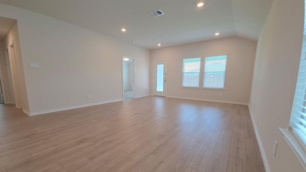 Spacious interior featuring wood-finish flooring, recessed lighting, and a vaulted ceiling Spacious interior featuring wood-finish flooring, recessed lighting, and a vaulted ceiling