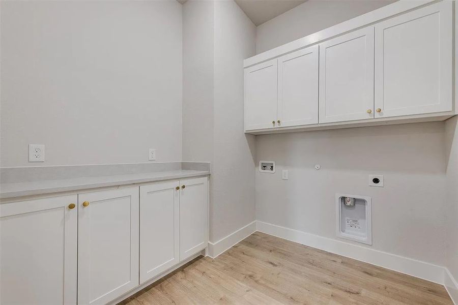 Laundry room with cabinet space, hookup for an electric dryer, washer hookup, gas dryer hookup, and light wood-type flooring