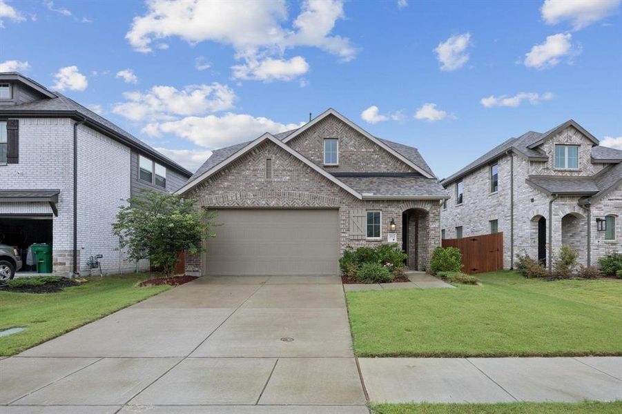 View of front facade featuring concrete driveway, brick siding, an attached garage, and roof with shingles