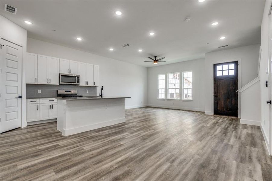 Kitchen with a center island with sink, white cabinets, ceiling fan, appliances with stainless steel finishes, and light hardwood / wood-style floors