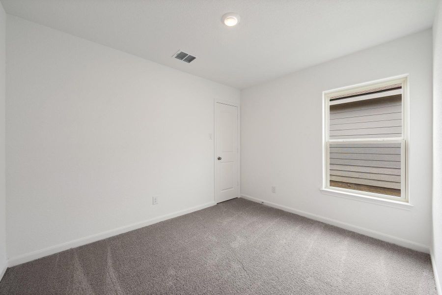A well-lit bedroom with fresh gray carpet awaits your personal touch.