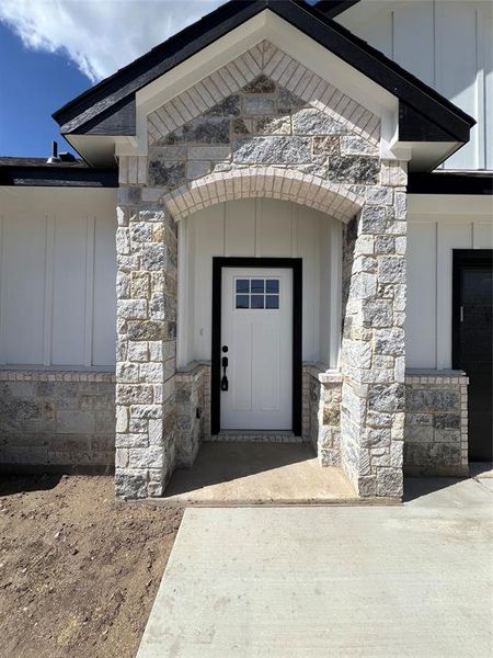 Doorway to property featuring board and batten siding and stone siding