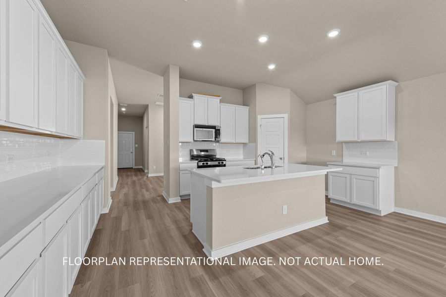 A well-appointed kitchen features a central island, ample cabinetry, and rich wood flooring.