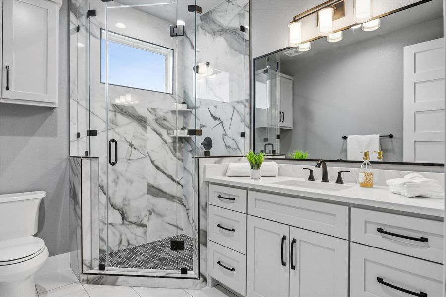 Bathroom featuring a marble finish shower and vanity