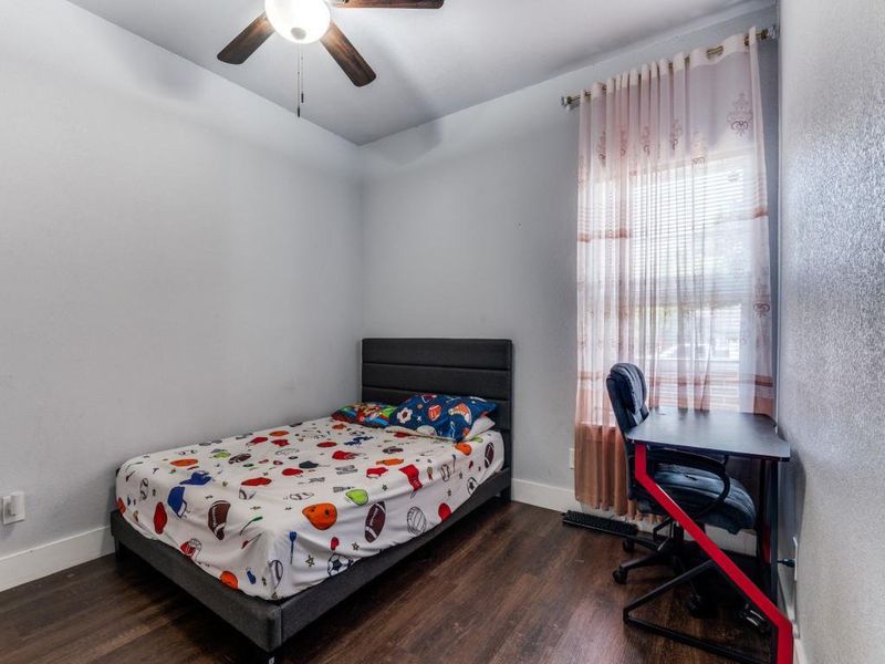 Bedroom with dark wood-style floors, a ceiling fan, and a textured wall Bedroom with dark wood-style floors, a ceiling fan, and a textured wall
