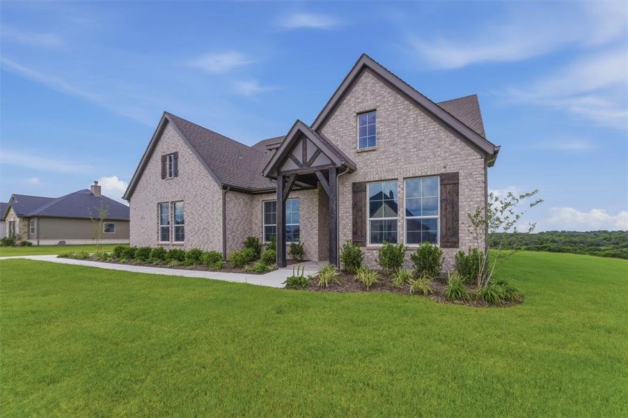 New construction home featuring a light-colored brick exterior, dark gabled roofing, and a prominent dark wood entry porch New construction home featuring a light-colored brick exterior, dark gabled roofing, and a prominent dark wood entry porch