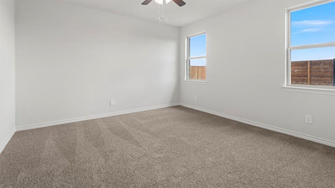 Carpeted empty room featuring baseboards and ceiling fan