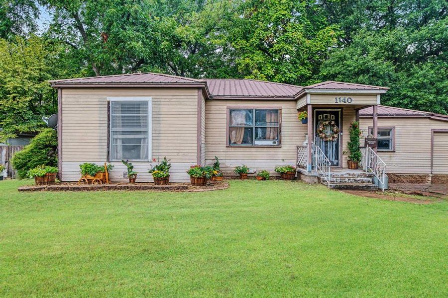 View of front of property with a metal roof, a front yard, and view of scattered trees View of front of property with a metal roof, a front yard, and view of scattered trees