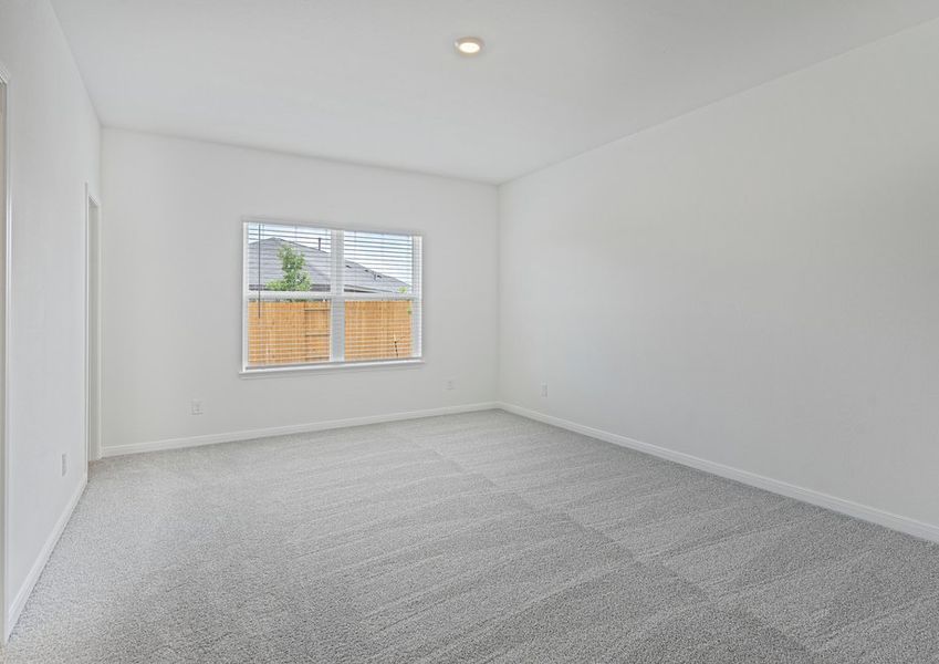 Master bedroom with a large window overlooking the private backyard