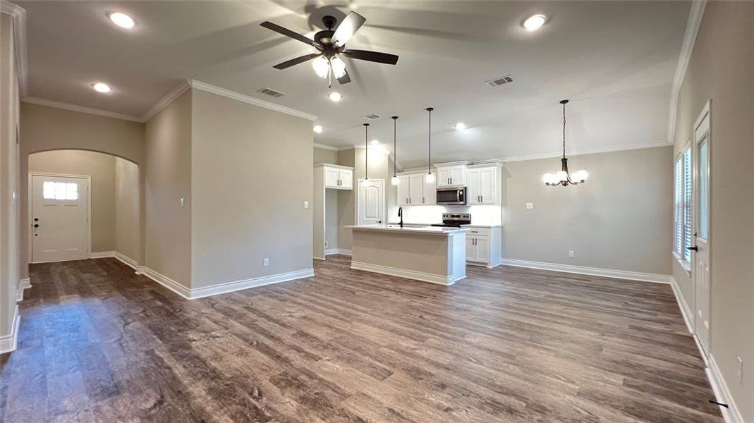 Kitchen featuring appliances with stainless steel finishes, white cabinets, hardwood / wood-style floors, and a kitchen island with sink
