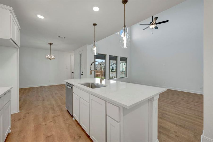 Kitchen with white cabinetry, open floor plan, light wood finished floors, an island with sink, and lofted ceiling