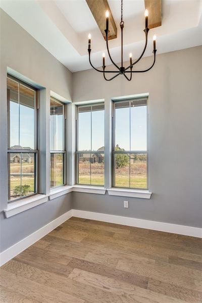 Unfurnished dining area featuring wood finished floors and a chandelier Unfurnished dining area featuring wood finished floors and a chandelier