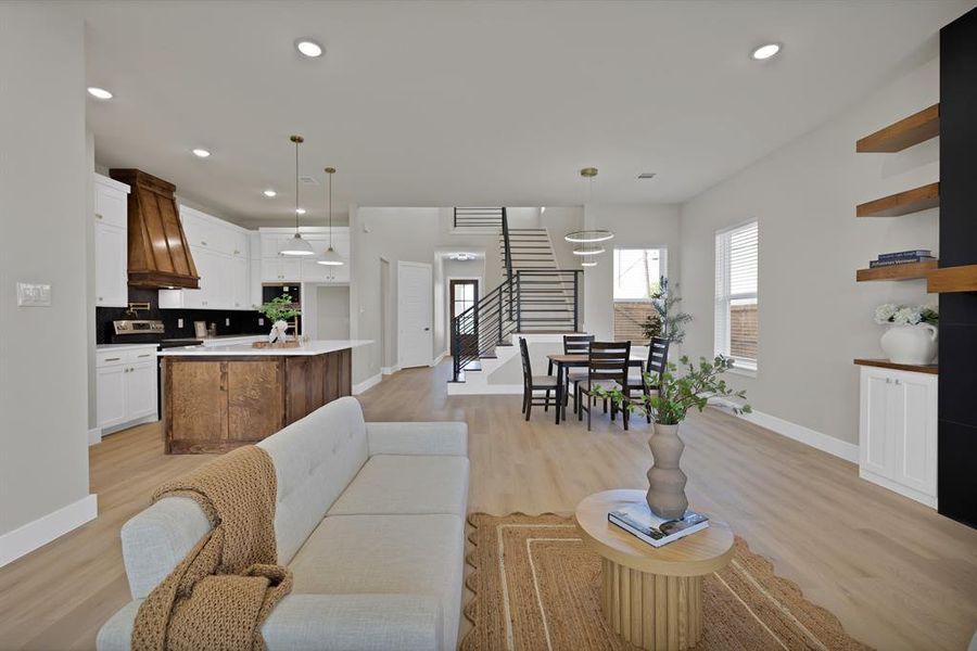 Living area featuring baseboards, light wood-style floors, recessed lighting, and stairs Living area featuring baseboards, light wood-style floors, recessed lighting, and stairs