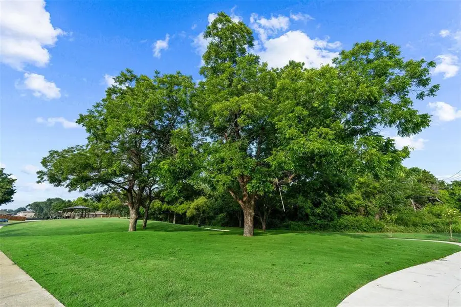 View of home's community with a lawn and view of scattered trees View of home's community with a lawn and view of scattered trees