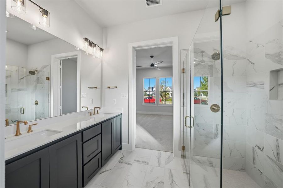 Bathroom with a marble finish shower, double vanity, light marble finish floors, and ceiling fan