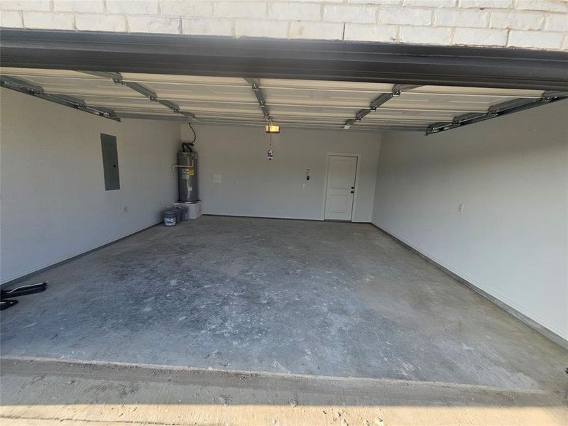 Garage featuring electric water heater and electric panel