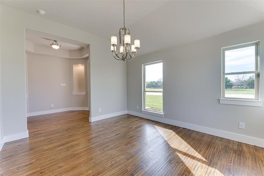 Unfurnished room with a wealth of natural light, an inviting chandelier, and hardwood / wood-style flooring