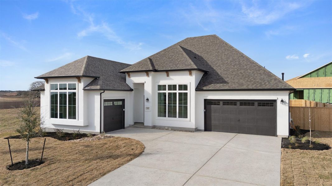 French country style house featuring roof with shingles, an attached garage, and stucco siding