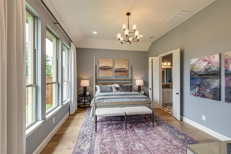 Bedroom with a notable chandelier, light hardwood / wood-style flooring, connected bathroom, and vaulted ceiling