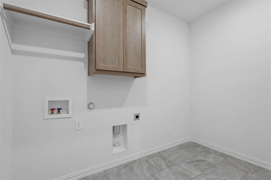 Clothes washing area with cabinets, hookup for a washing machine, electric dryer hookup, and gas dryer hookup