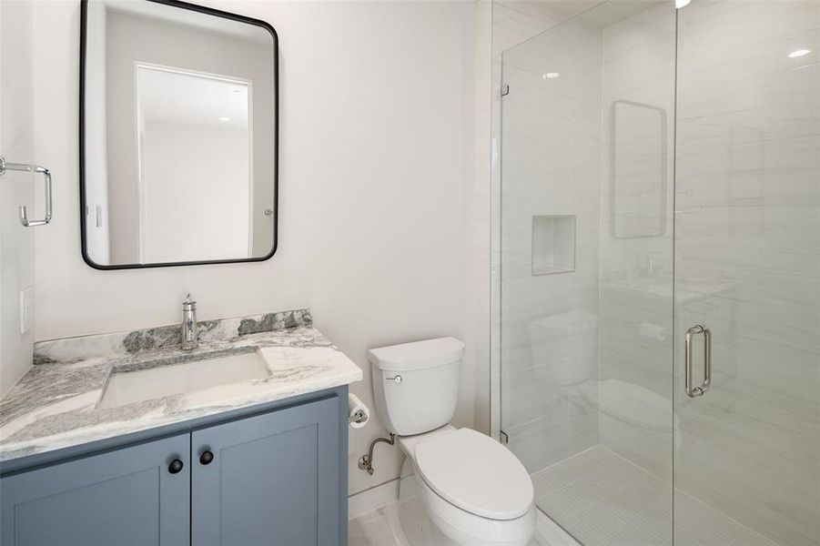 Bathroom with a shower with door, vanity, and toilet