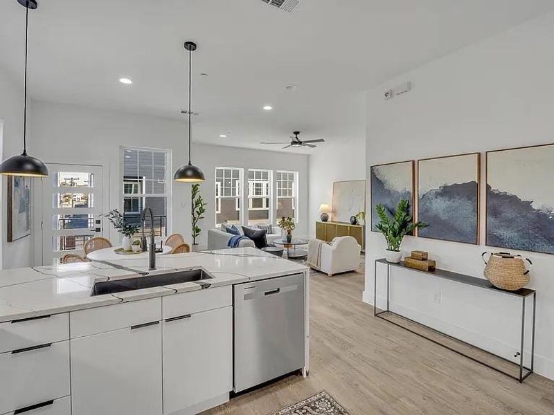 Kitchen featuring white cabinets, hanging light fixtures, light wood-style floors, stainless steel dishwasher, and a ceiling fan