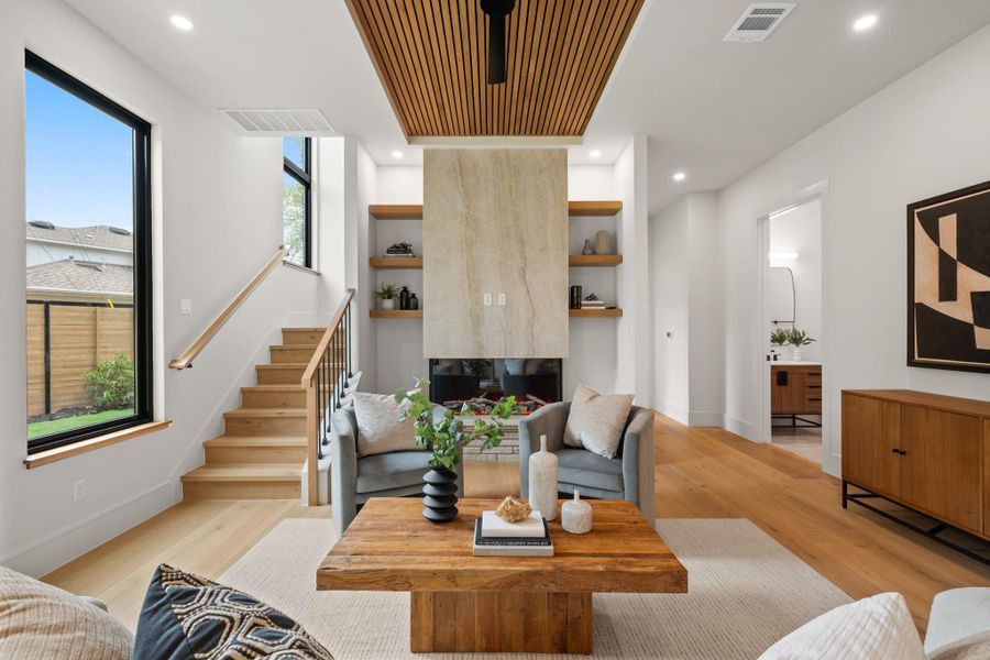 Warm wood floors and a custom stone fireplace anchor this soaring contemporary living space.