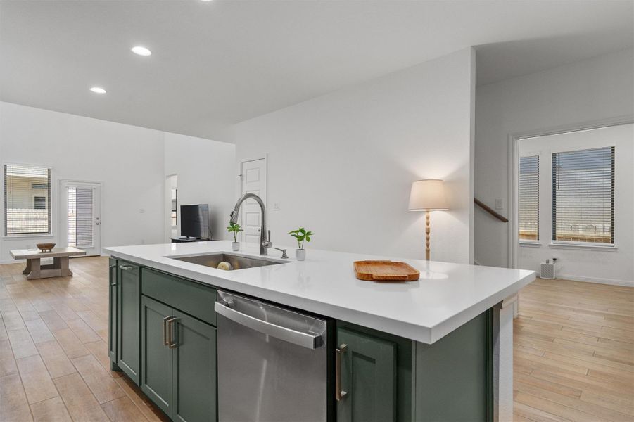 Kitchen with green cabinets, dishwasher, an island with sink, light wood-type flooring, and recessed lighting