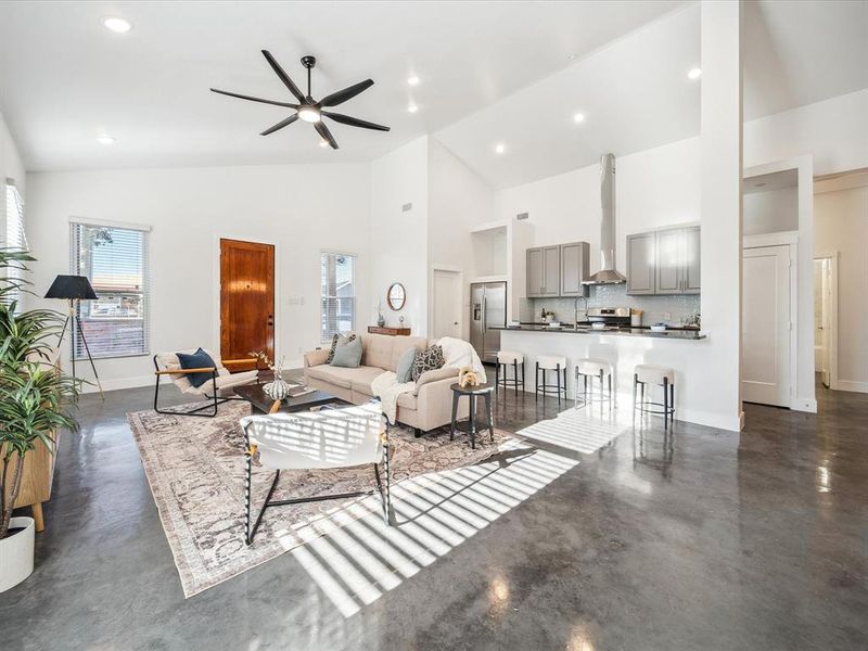 Living room featuring high vaulted ceiling, ceiling fan, and sink