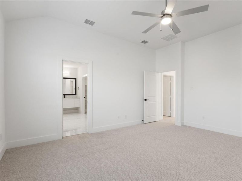 Primary bedroom with carpet, a ceiling fan, ensuite bath, and vaulted ceiling